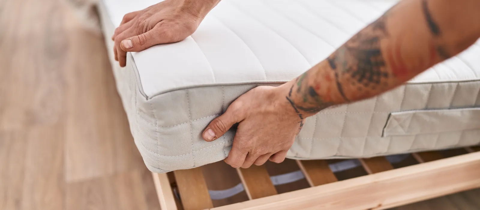 1761236231-young-man-holding-mattress-bedroom (1)